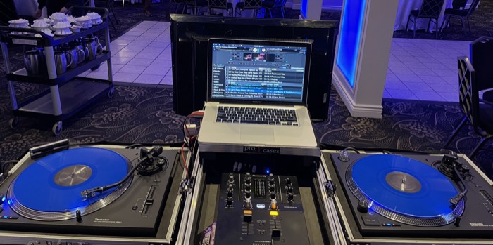 Don of Sound DJ booth with twin Technics turntables, blue vinyl records, and a Pioneer DJ mixer at an event