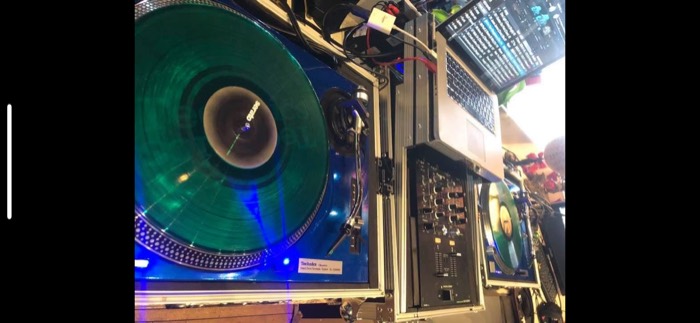 Close-up of a green vinyl record spinning on a blue Technics turntable